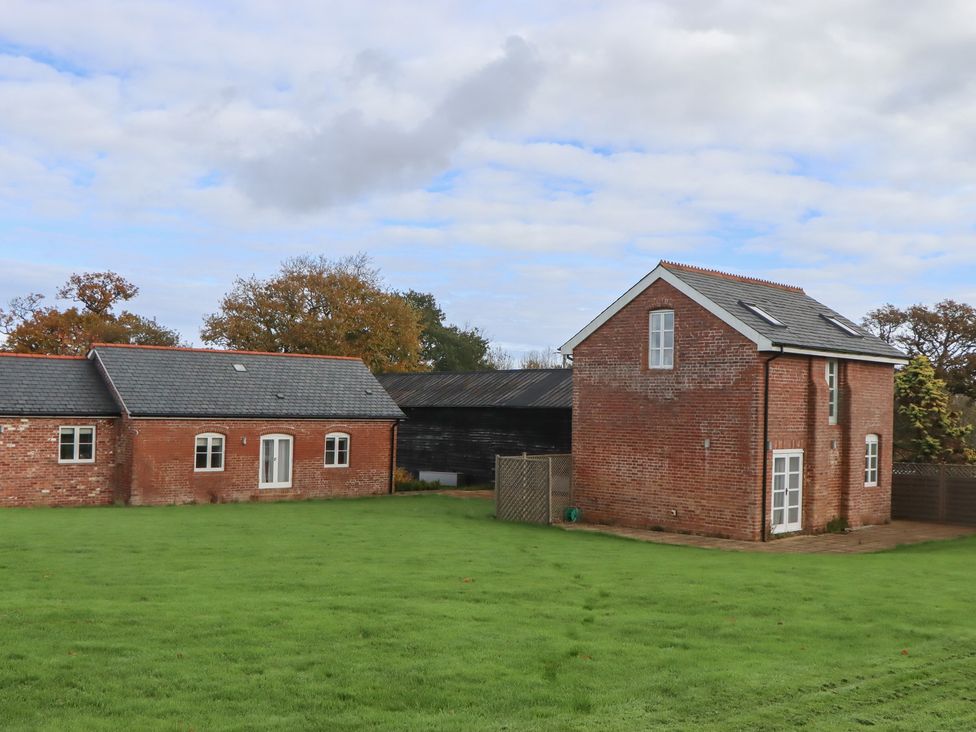 A building with a large lawn and trees at Hilldown Granary in Crediton