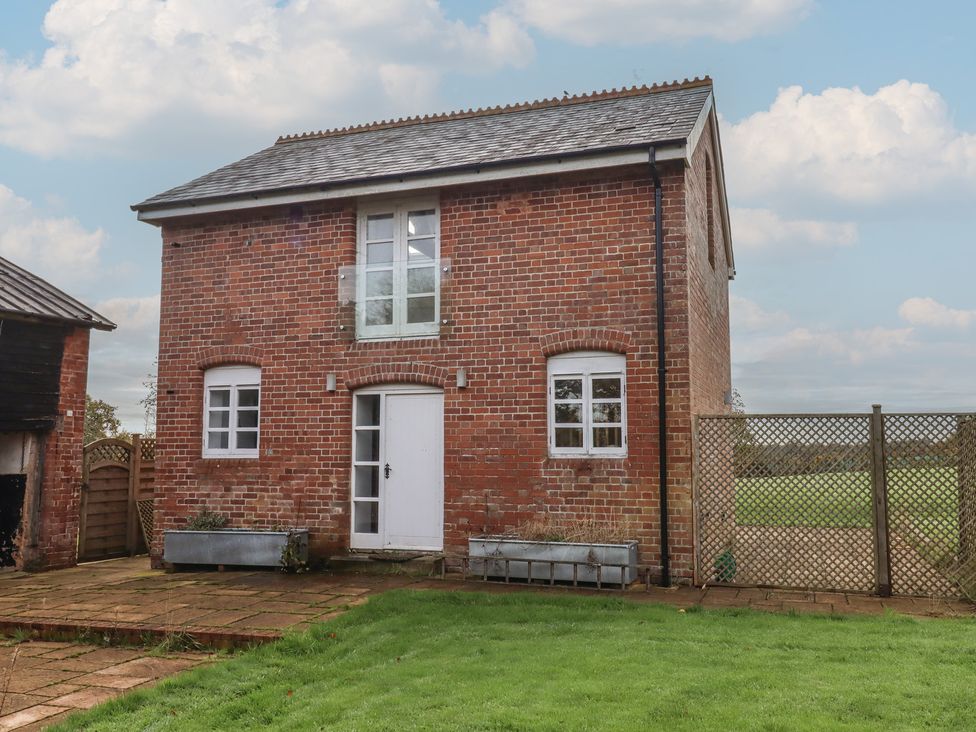 A brick house with lawn and fence at Hilldown Granary in Crediton