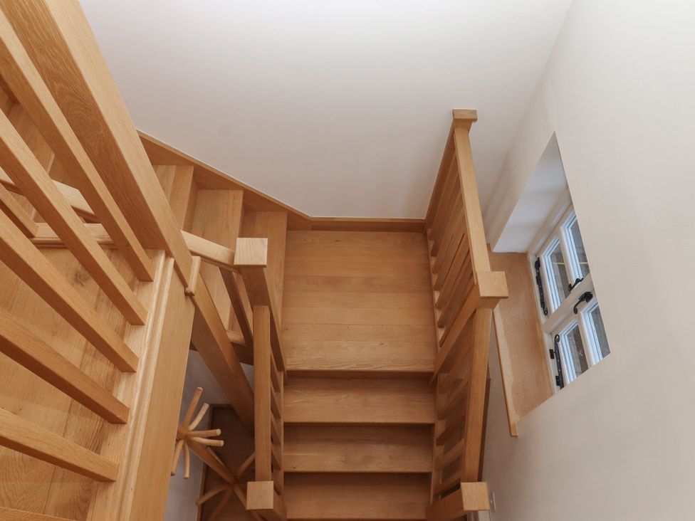 A wooden staircase with a railing and a window at Hilldown Granary near Bow