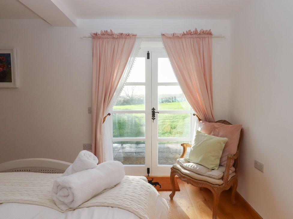 A bedroom with a bed and a chair at Hilldown Granary near Bow