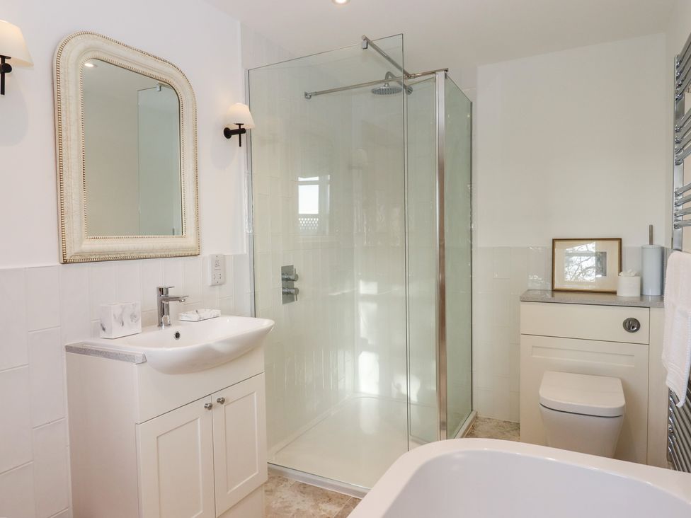 A bathroom with a shower, sink, and toilet at Hilldown Granary near Bow