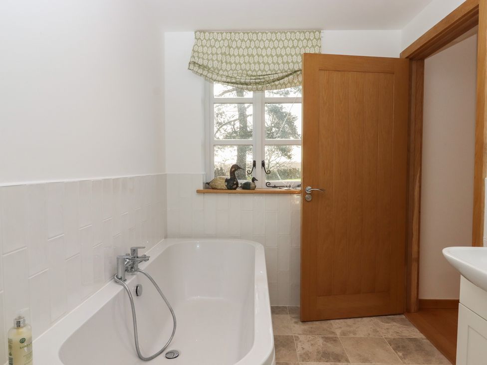 A bathroom with a bathtub and a window at Hilldown Granary near Bow