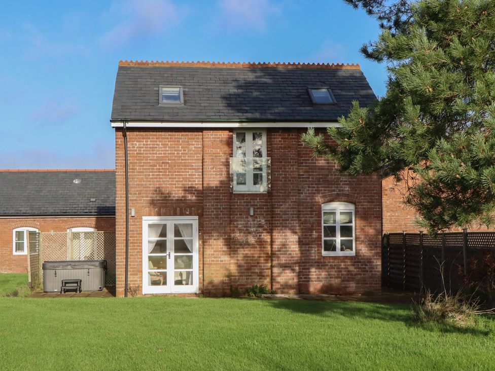 A brick building with windows and a hot tub near Hilldown Granary near Bow
