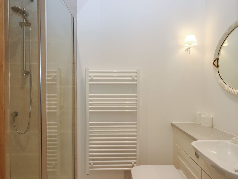 A bathroom with a shower, sink, and towel rail at Hilldown Cott near Bow