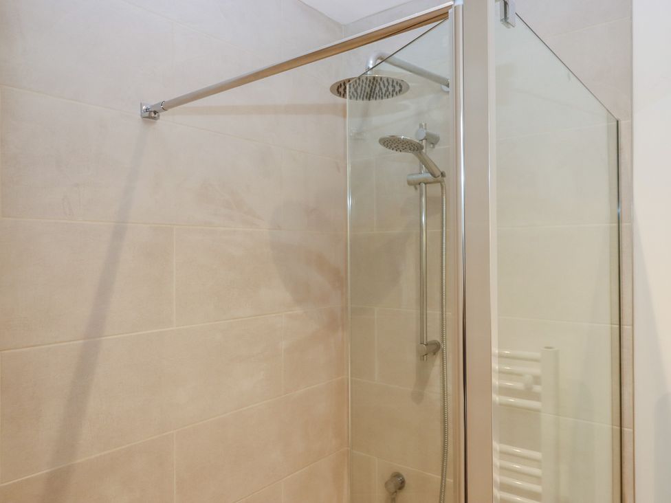 A shower with glass enclosure and towel radiator at Hilldown Cott near Bow