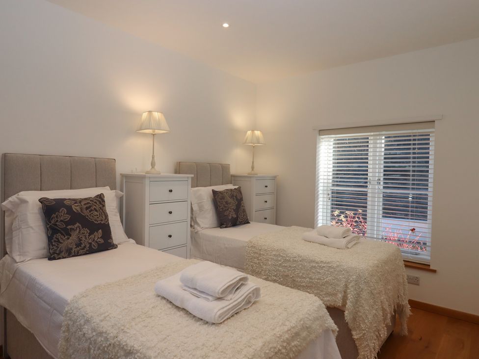 A bedroom with two single beds and a window at Hilldown Cott near Bow