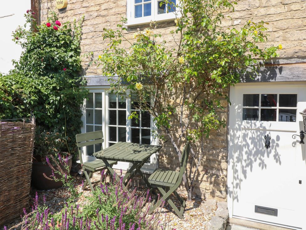 A table and chair set next to a door and window at Freya Cottage in Metheringham