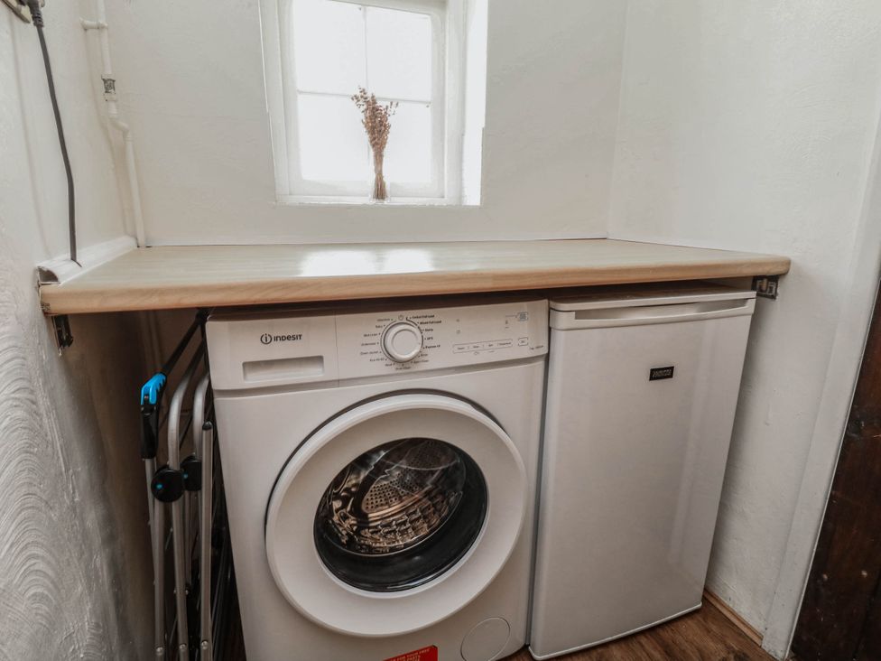 A laundry room with a washing machine and fridge at Freya Cottage in Metheringham