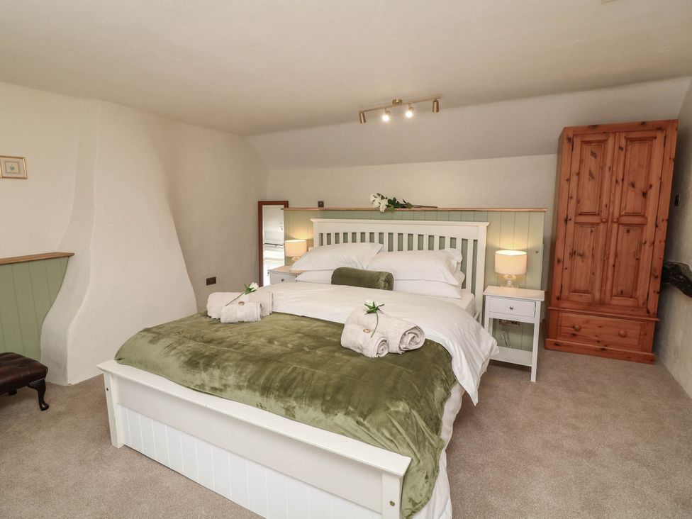 A bedroom with a bed and wardrobe at Freya Cottage in Metheringham