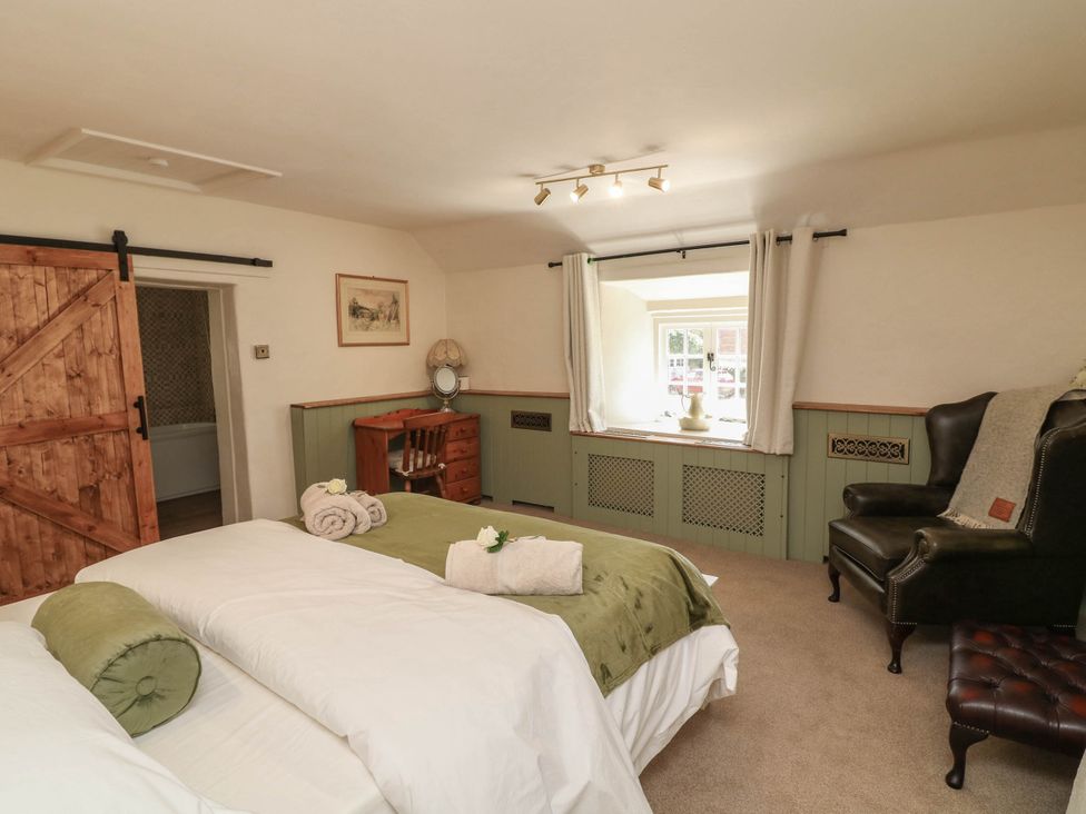 A bedroom with a bed, desk and window at Freya Cottage in Metheringham