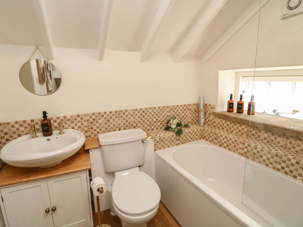 A bathroom with a bath tub, sink, and toilet at Freya Cottage in Metheringham
