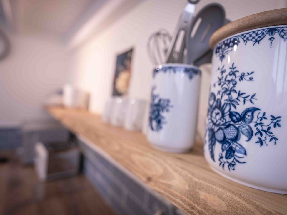 A kitchen shelf with jars and utensils at Freya's Cottage in Metheringham
