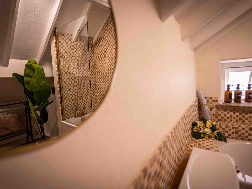 A bathroom with a bathtub and a mirror at Freya's Cottage in Metheringham