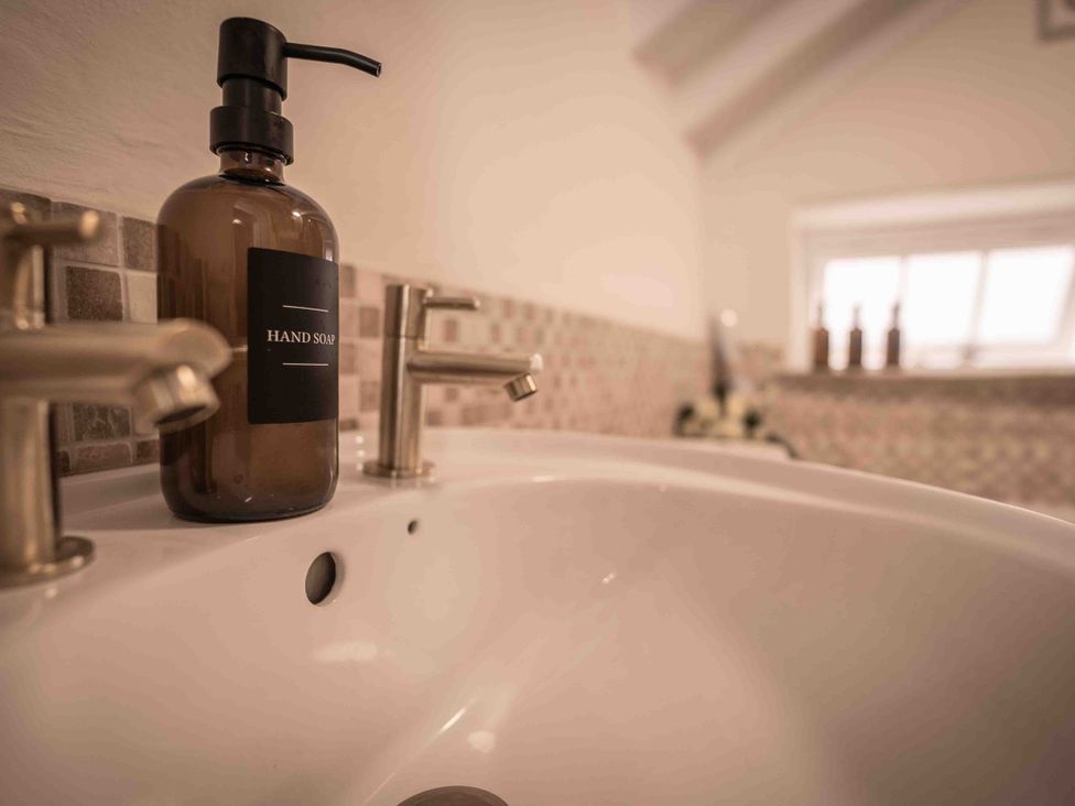 A sink with a hand soap bottle and faucets at Freya's Cottage in Metheringham