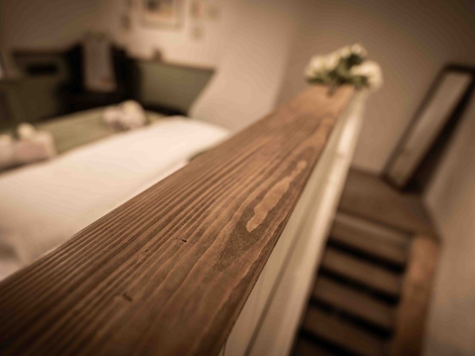 A bedroom with a wooden railing and flowers at Freya's Cottage in Metheringham