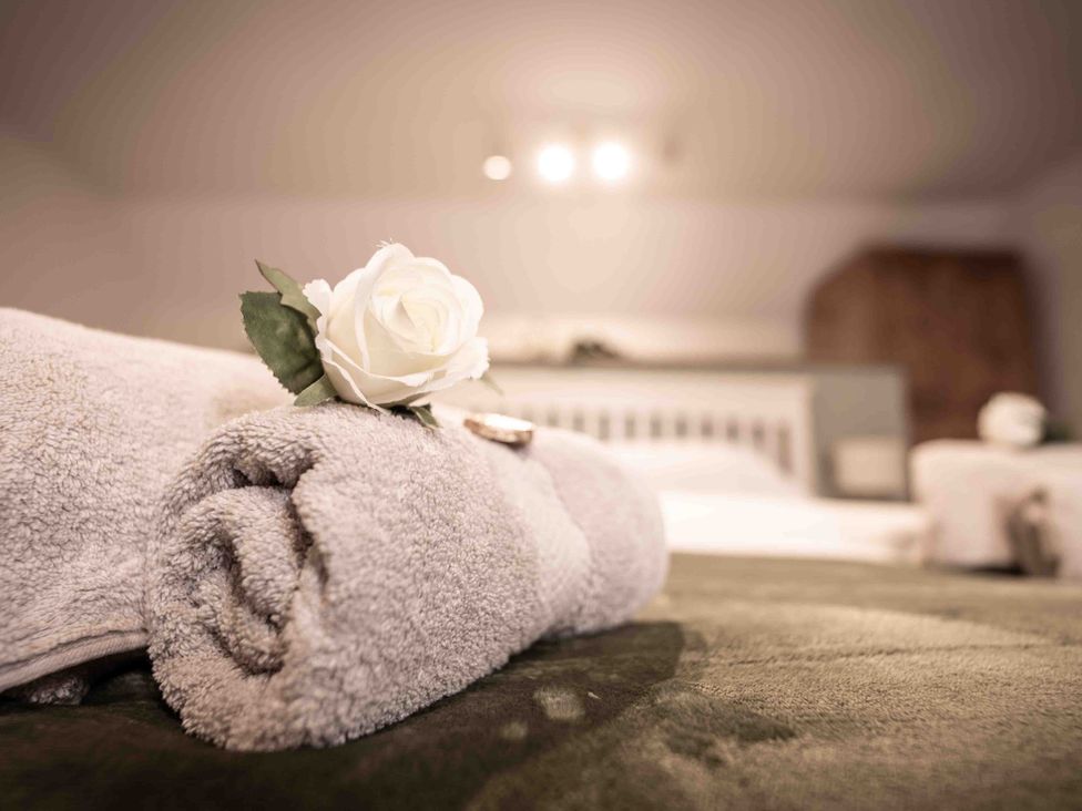 A towel with a rose on top in a bedroom at Freya's Cottage Metheringham