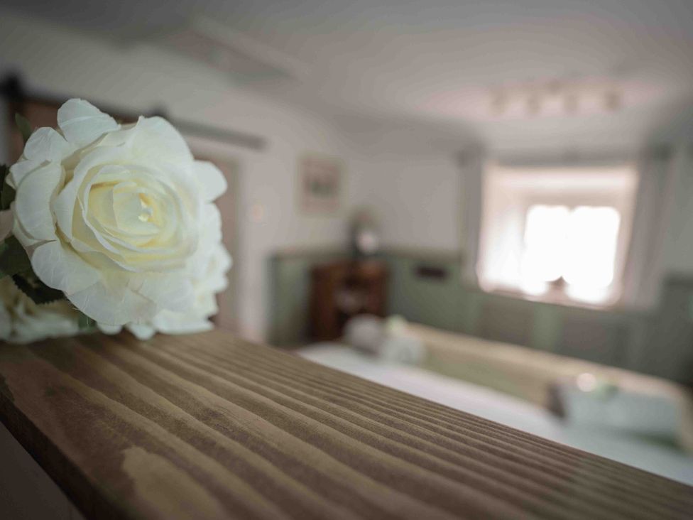 A flower on a wooden surface in a bedroom at Freya's Cottage in Metheringham