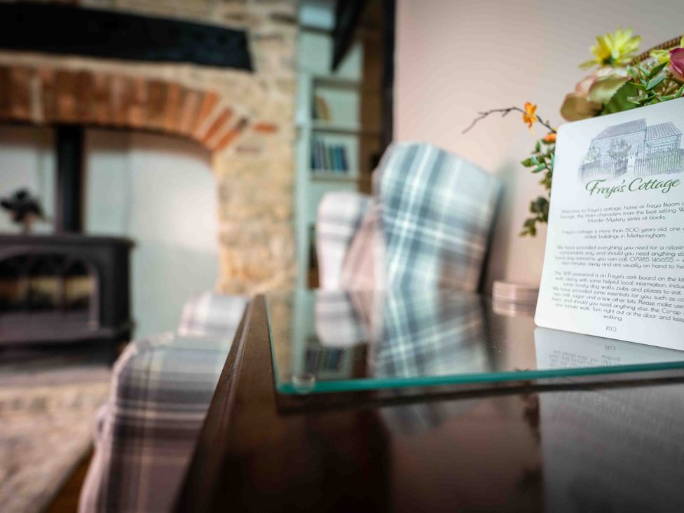 A living room with a fireplace and information card at Freya's Cottage in Metheringham