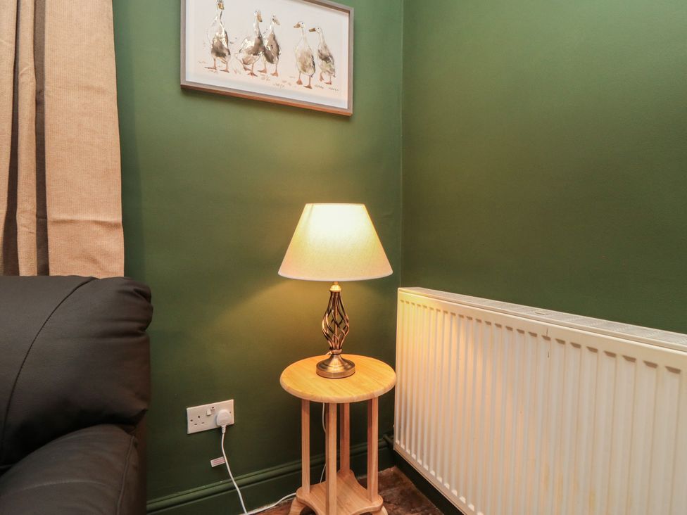 A corner of a living room with a lamp and artwork at Daisy cottage in Pickering