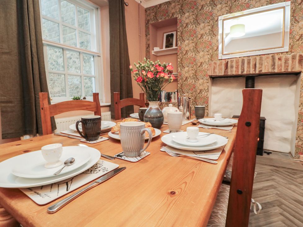 A dining room with a wooden table set for a meal at Daisy cottage in Pickering