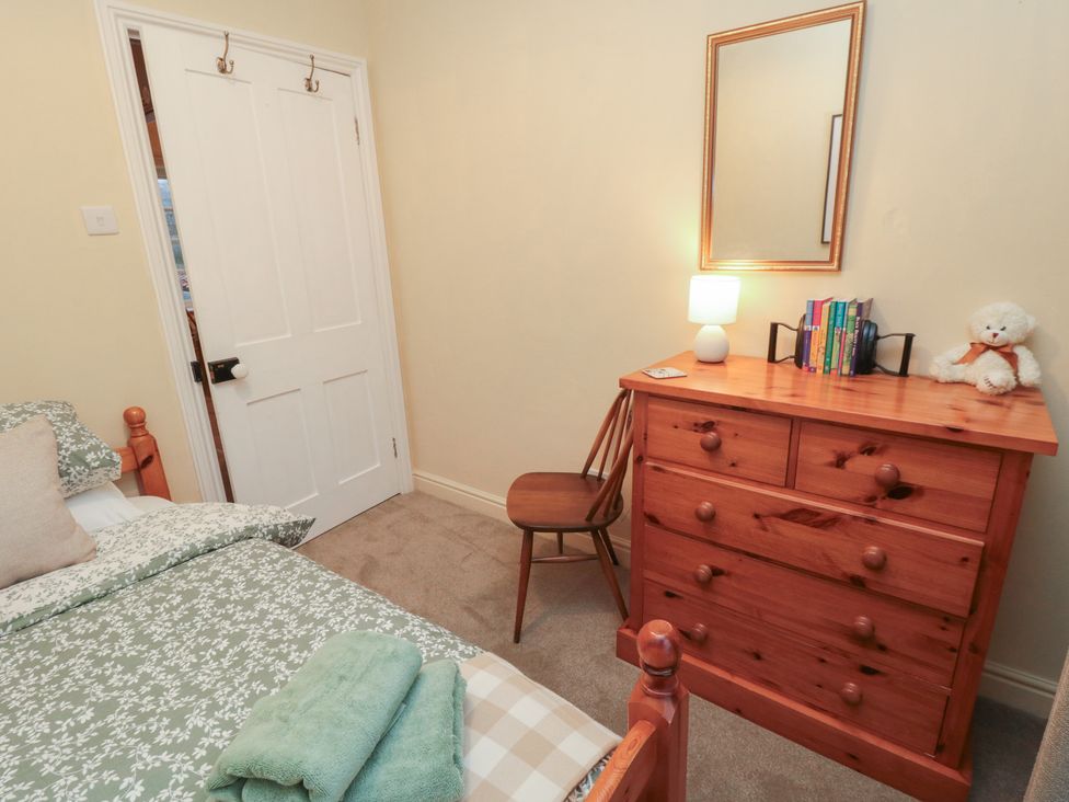 A bedroom with a bed, dresser, chair, and a lamp at Daisy cottage, Pickering