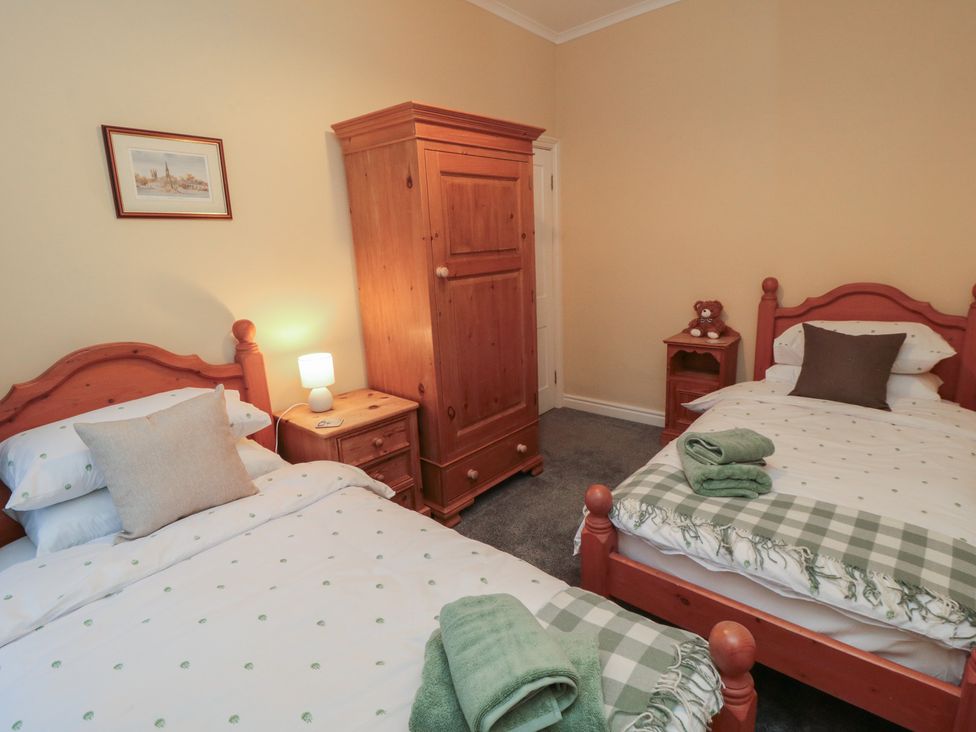 A bedroom with two beds and a wardrobe at Daisy cottage in Pickering