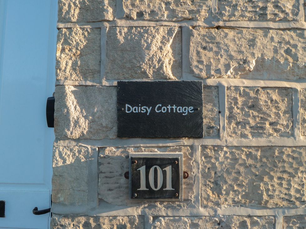 A house sign and number 101 on a stone wall at Daisy cottage in Pickering