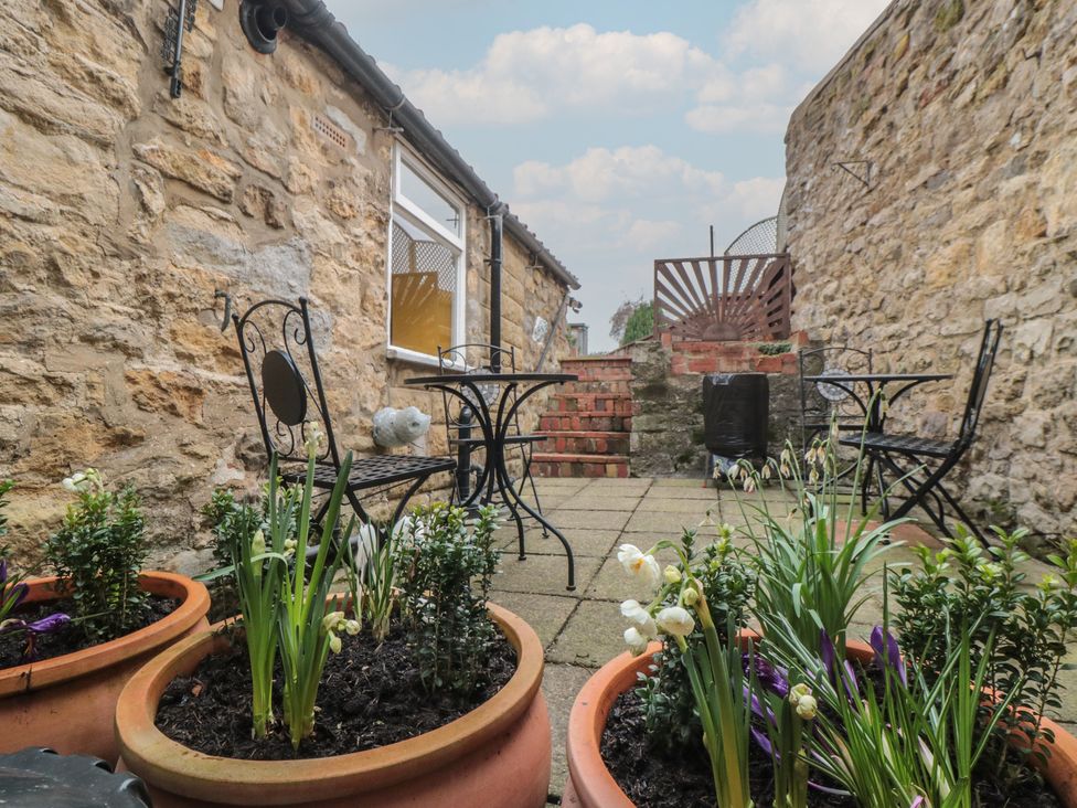 A garden with potted plants and seating area at Daisy cottage in Pickering