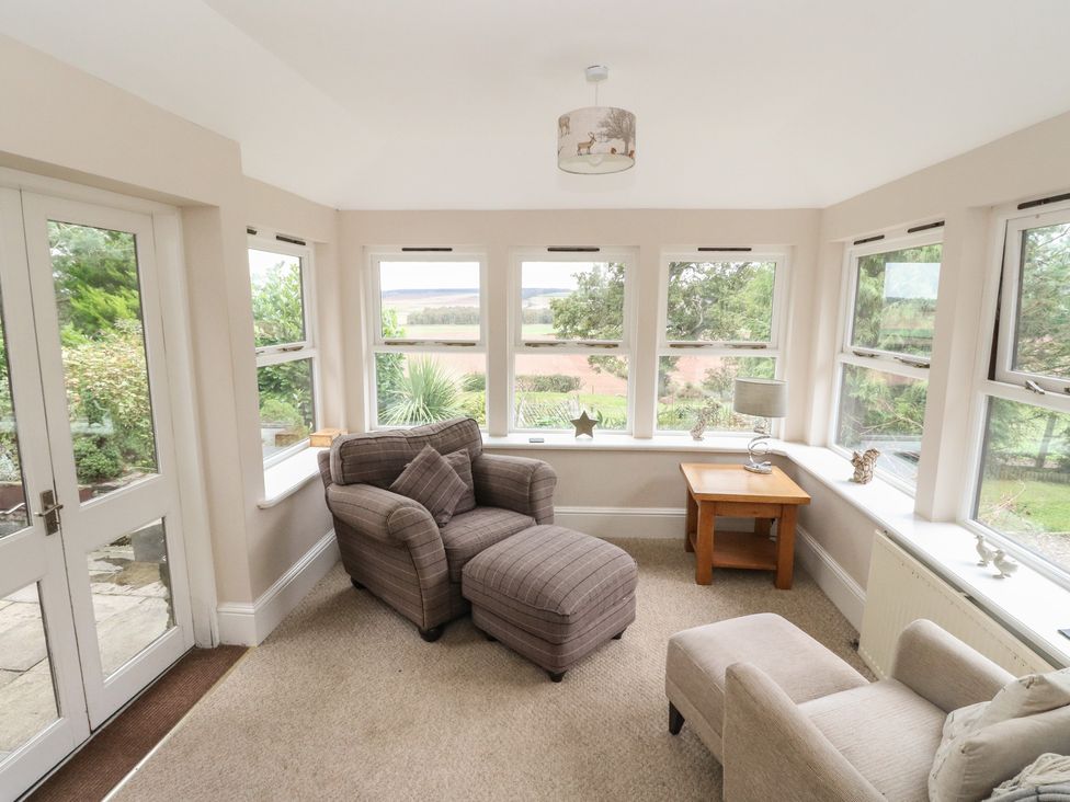 A conservatory with seating and views of the garden at The Cottage in Perth