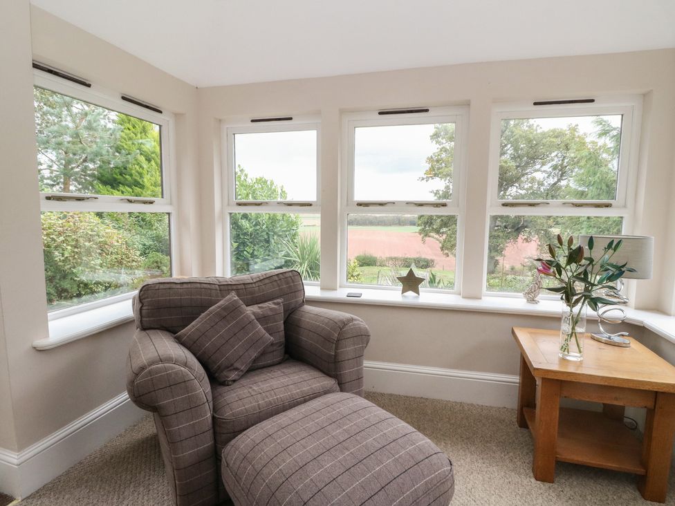 A snug with an armchair and table by the window at The Cottage in Perth
