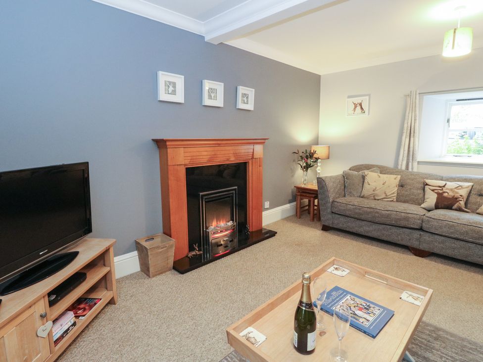 A living room with a fireplace and sofa at The Cottage in Perth