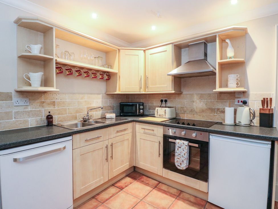 A kitchen with cabinets, stove, sink, and appliances at The Cottage in Perth