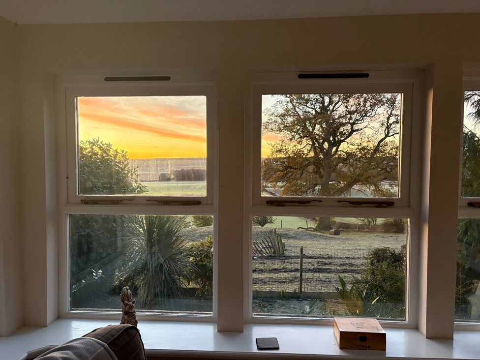 A view of a sunset outside the window in the living room at The Cottage in Methven