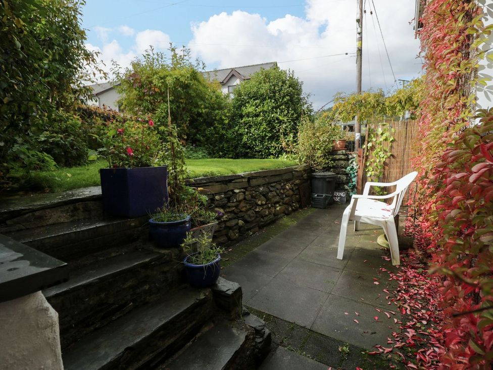 A garden with a stone wall and chair at Noddfa in Penmachno