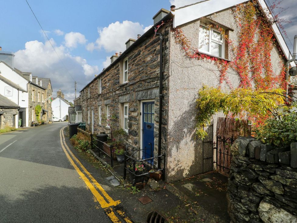 A stone house with a blue door and plants in the outdoor area at Noddfa Penmachno