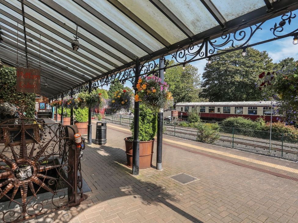 An outdoor train station platform with planters and a train at Noddfa Penmachno