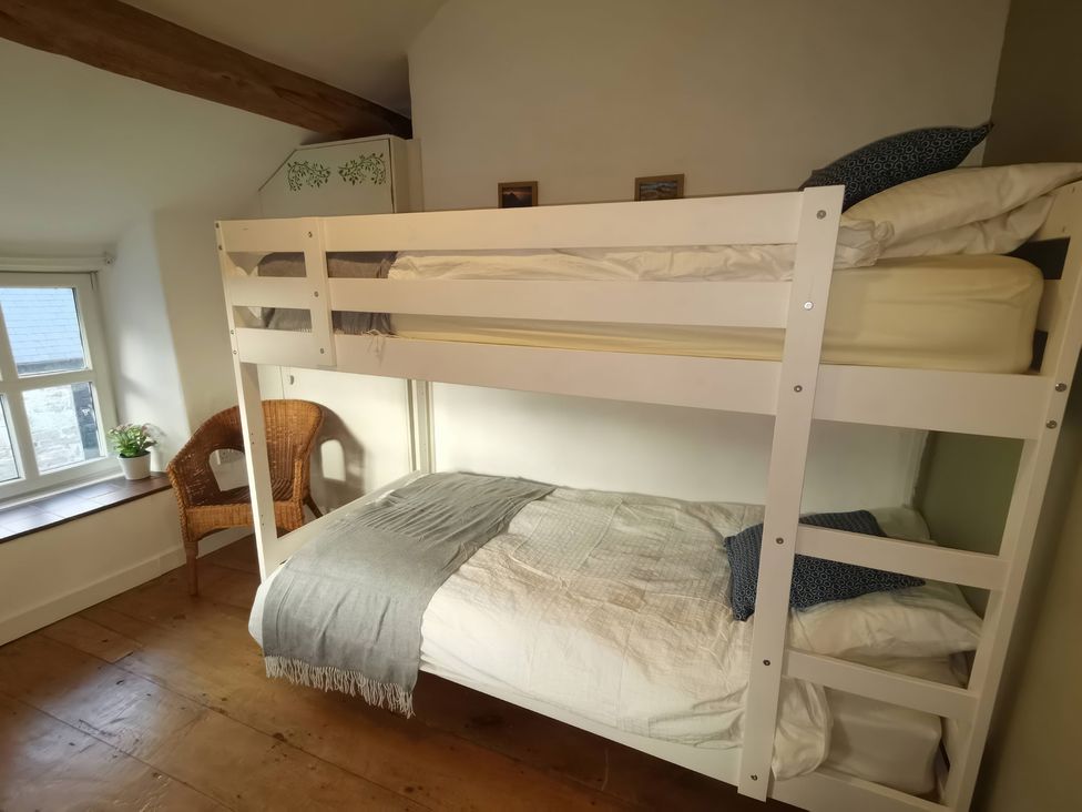 A bedroom with a bunk bed and wicker chair at Noddfa in Penmachno