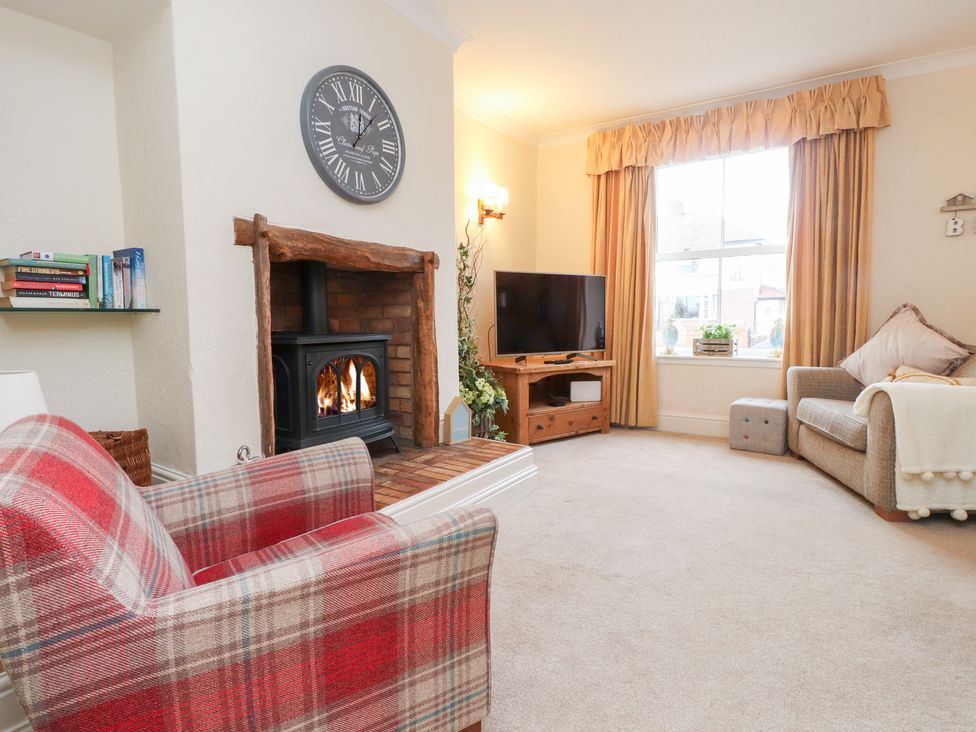 A living room with a fireplace and television at The Hideaway in Penrhyn Bay