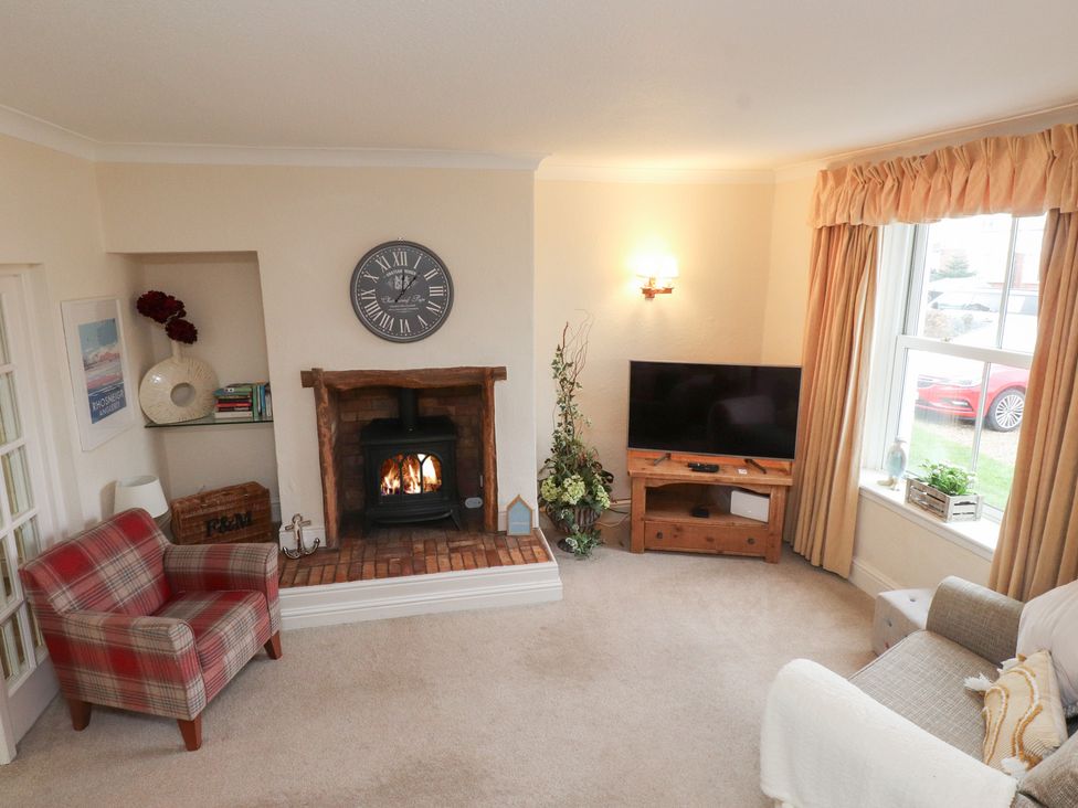 A living room with a fireplace and television at The Hideaway Penrhyn Bay