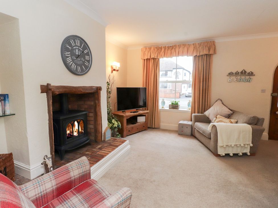 A living room with a fireplace and television at The Hideaway in Penrhyn Bay