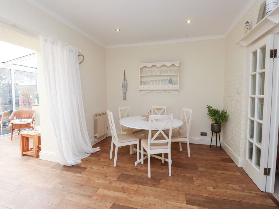 A dining room with a round table and chairs at The Hideaway in Penrhyn Bay
