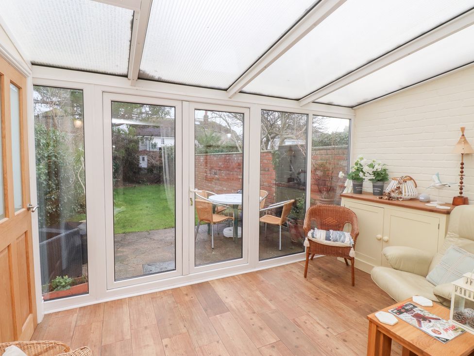 A conservatory with a table and chairs at The Hideaway in Penrhyn Bay