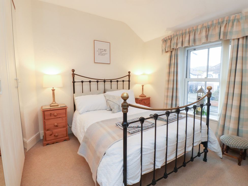 A bedroom with a bed and nightstand with lamp at The Hideaway in Penrhyn Bay