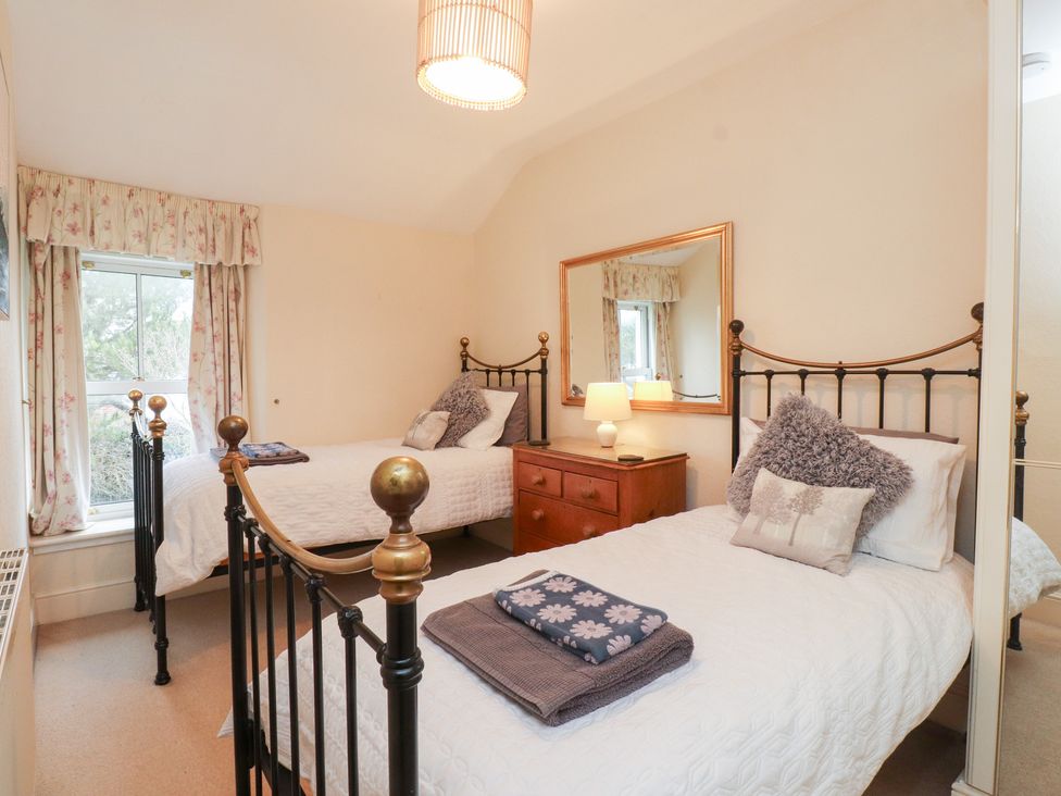 A bedroom with two beds and a bedside table at The Hideaway Penrhyn Bay