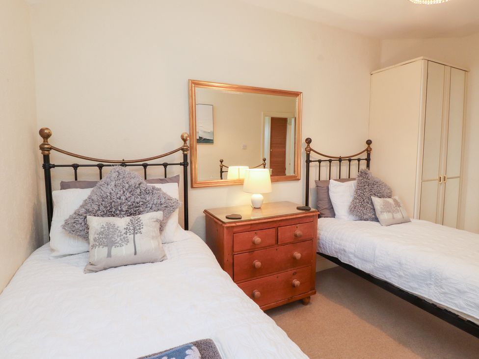 A bedroom with two beds and a bedside table at The Hideaway in Penrhyn Bay