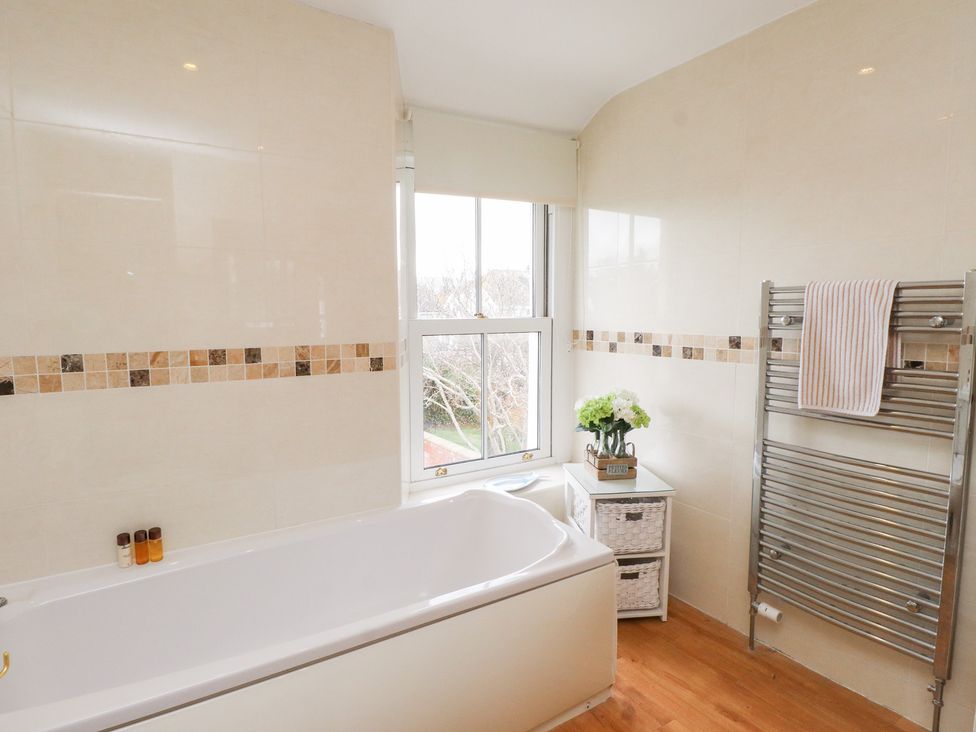 A bathroom with a bathtub and towel rack at The Hideaway in Penrhyn Bay