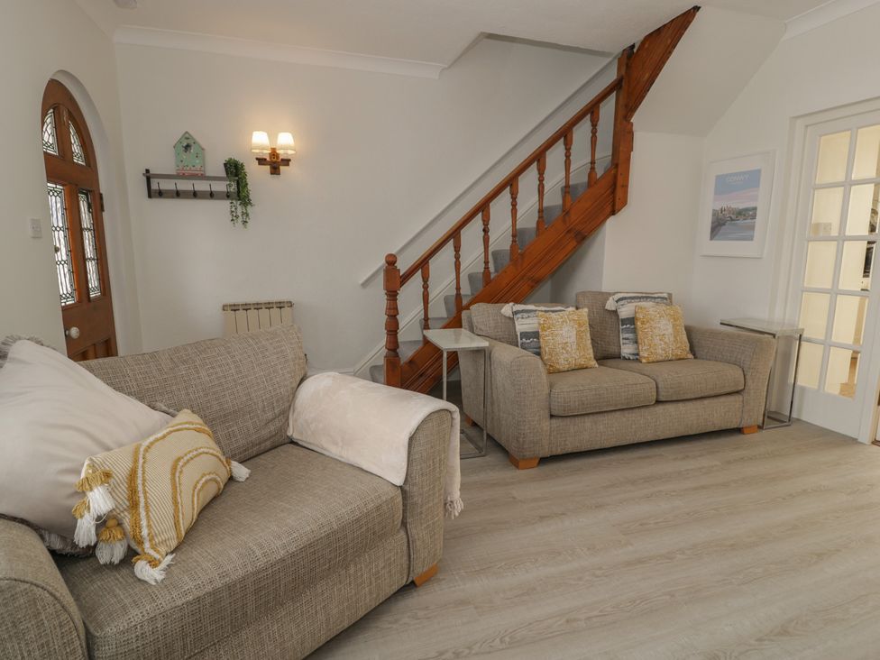 A living room with sofas and a staircase at The Hideaway in Penrhyn Bay