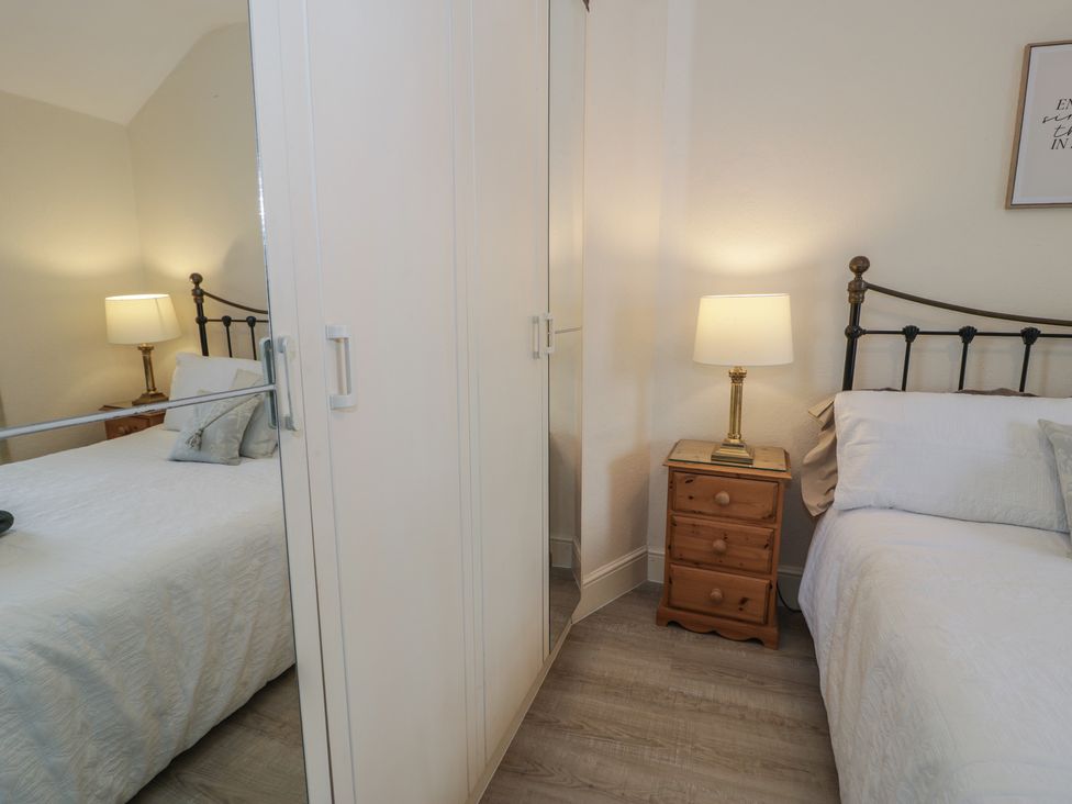 A bedroom with two beds and a wardrobe at The Hideaway Penrhyn Bay