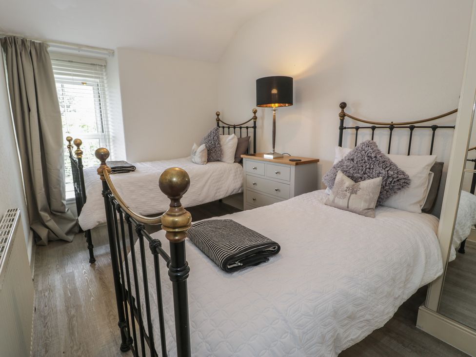 A bedroom with two beds and a nightstand at The Hideaway in Penrhyn Bay
