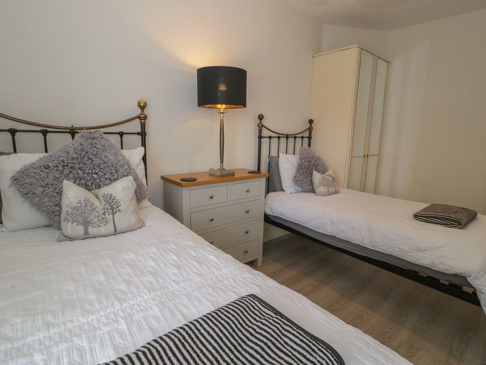 A bedroom with two single beds and a lamp at The Hideaway in Penrhyn Bay